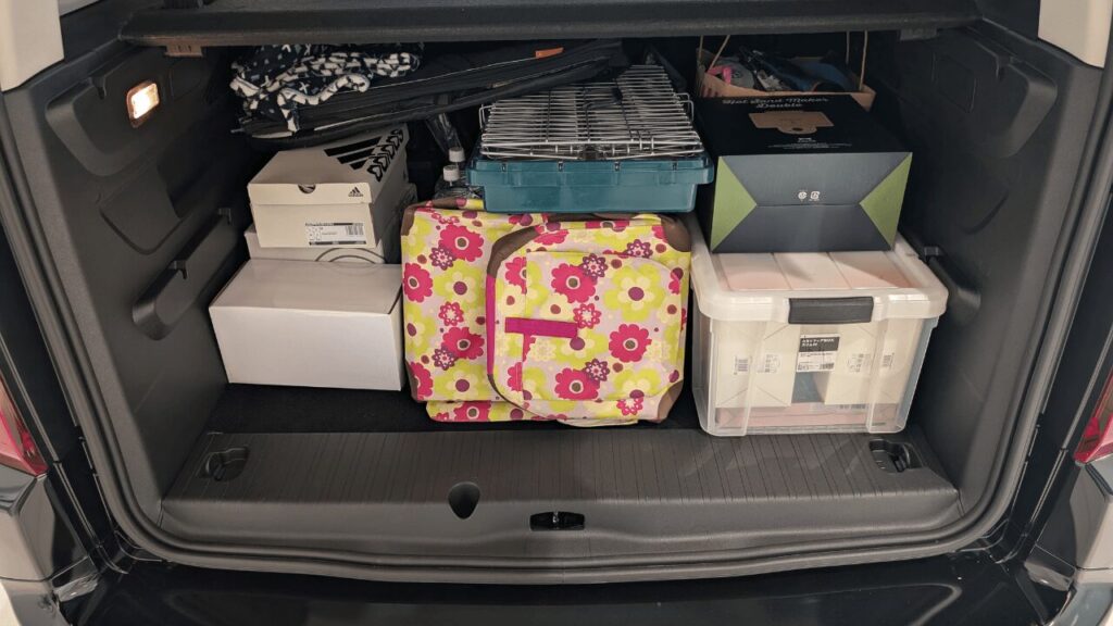 フィアット ドブロの広大な荷室（ラゲッジスペース）に、貸別荘用の荷物やコンテナが天井近くまで効率よく積載されている様子。